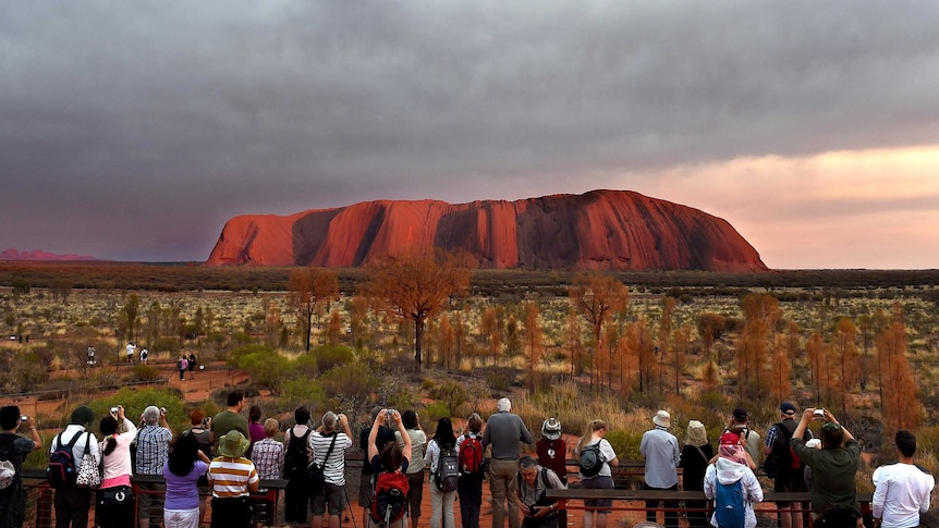 Visitors observe Uluru at sunrise.