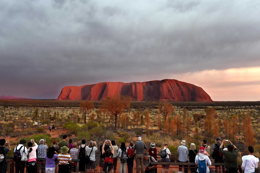 Visitors observe Uluru at sunrise.
