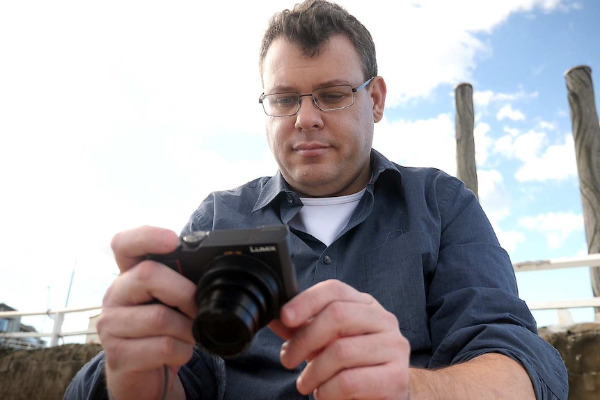 A man reviews images he's taken using a digital camera