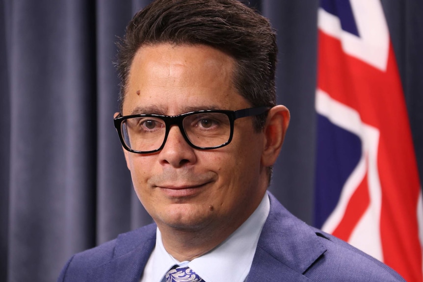 A close up of Ben Wyatt in the parliament house media room, in front of an Australian flag.