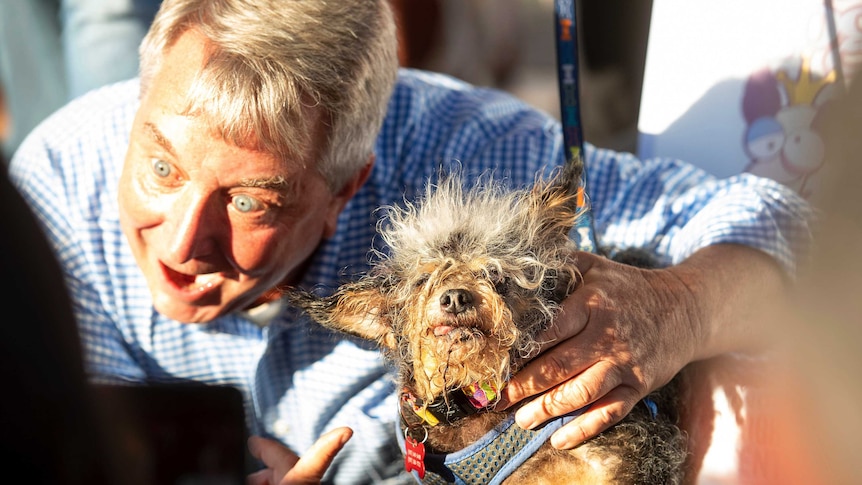A man gestures towards the dog which won this year's World's Ugliest Dog Contest.