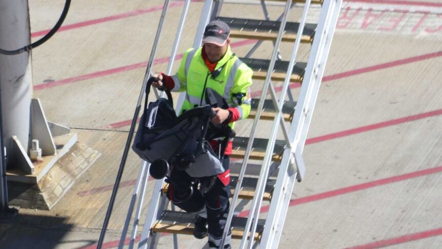 Staf bandara di Bandara Internasional Perth membawa turun kereta bayi dari pesawat AirAsia.