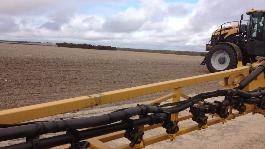 A self-propelled sprayer sitting at the edge of a clean paddock at seeding time in Western Australia