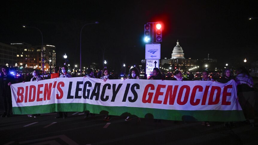Protestors in Washington hold a banner saying 'Biden's legacy is genocide'