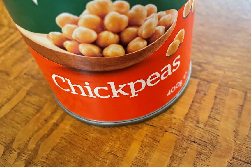 Close-up of a tin of chickpeas sitting on a silken oak countertop. 