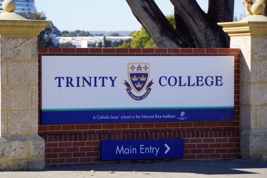 A sign at the entrance to Trinity College in Perth with the school's crest in the middle of the school's name.