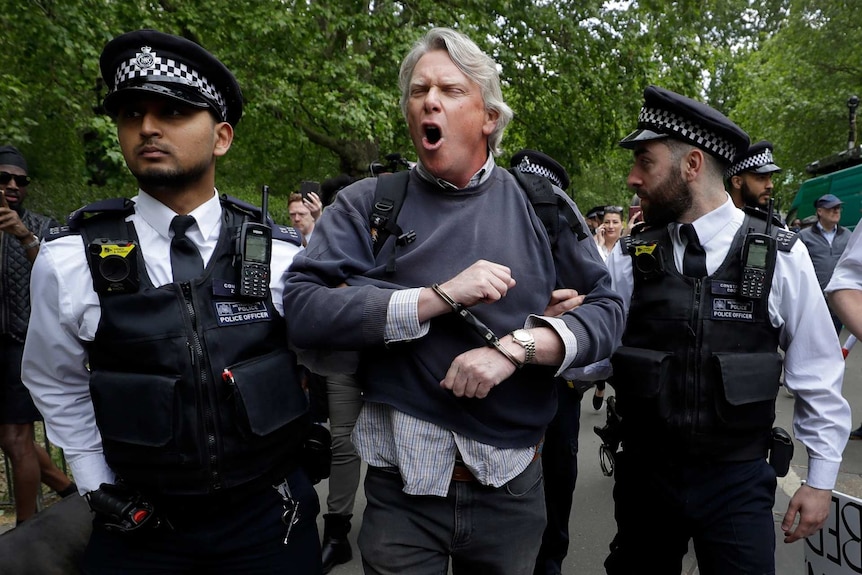 two police officers hold a man in handcuffs