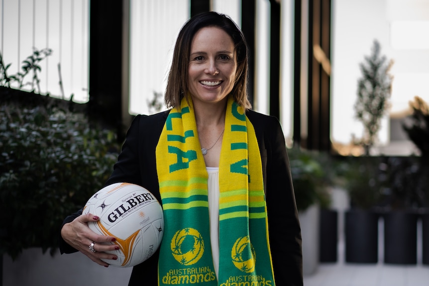 Kelly Ryan holds a netball under her arm and smiles.