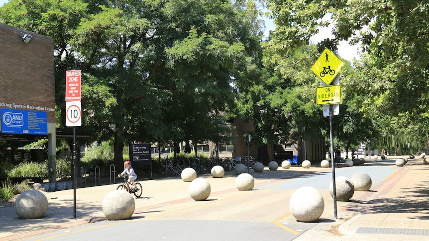 A child cycles through empty streets at the Australian National University.