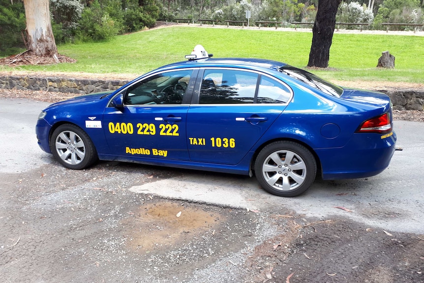A blue car with Apollo Bay Taxi written on its side.