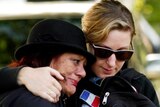 Two women hug at a memorial service to mark the first anniversary of the Christchurch earthquake.