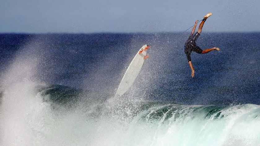 A surfer flips upside down after riding big waves