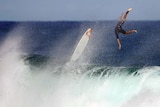 A surfer flips upside down after riding big waves