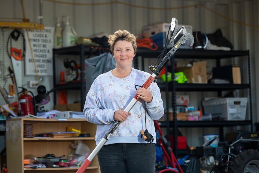 A woman holds a garden tool.