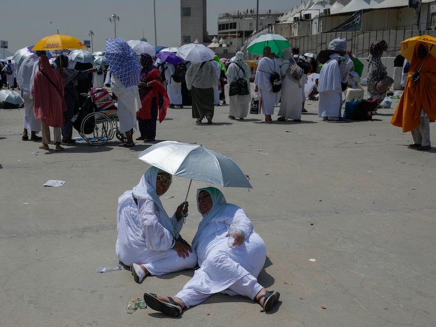 Women taking shade from extreme heat during hajj in Mecca