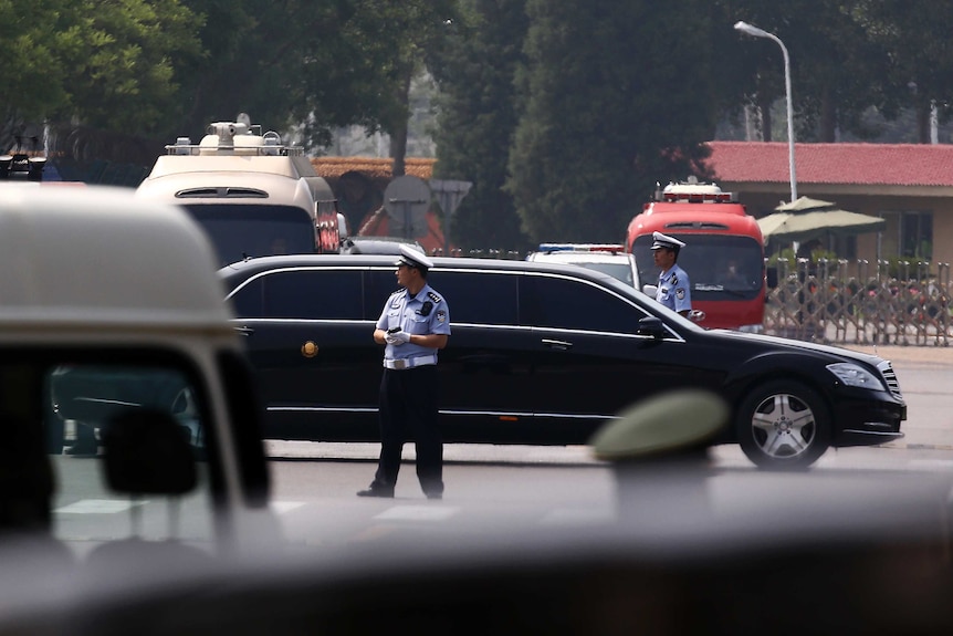 The motorcade which is believed to be carrying North Korea leader Kim Jong-un passes by policemen.