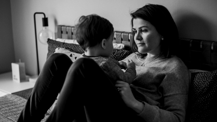 Sara Chivers, sitting up on a bed, plays with her son Alfie, while he sits on her stomach