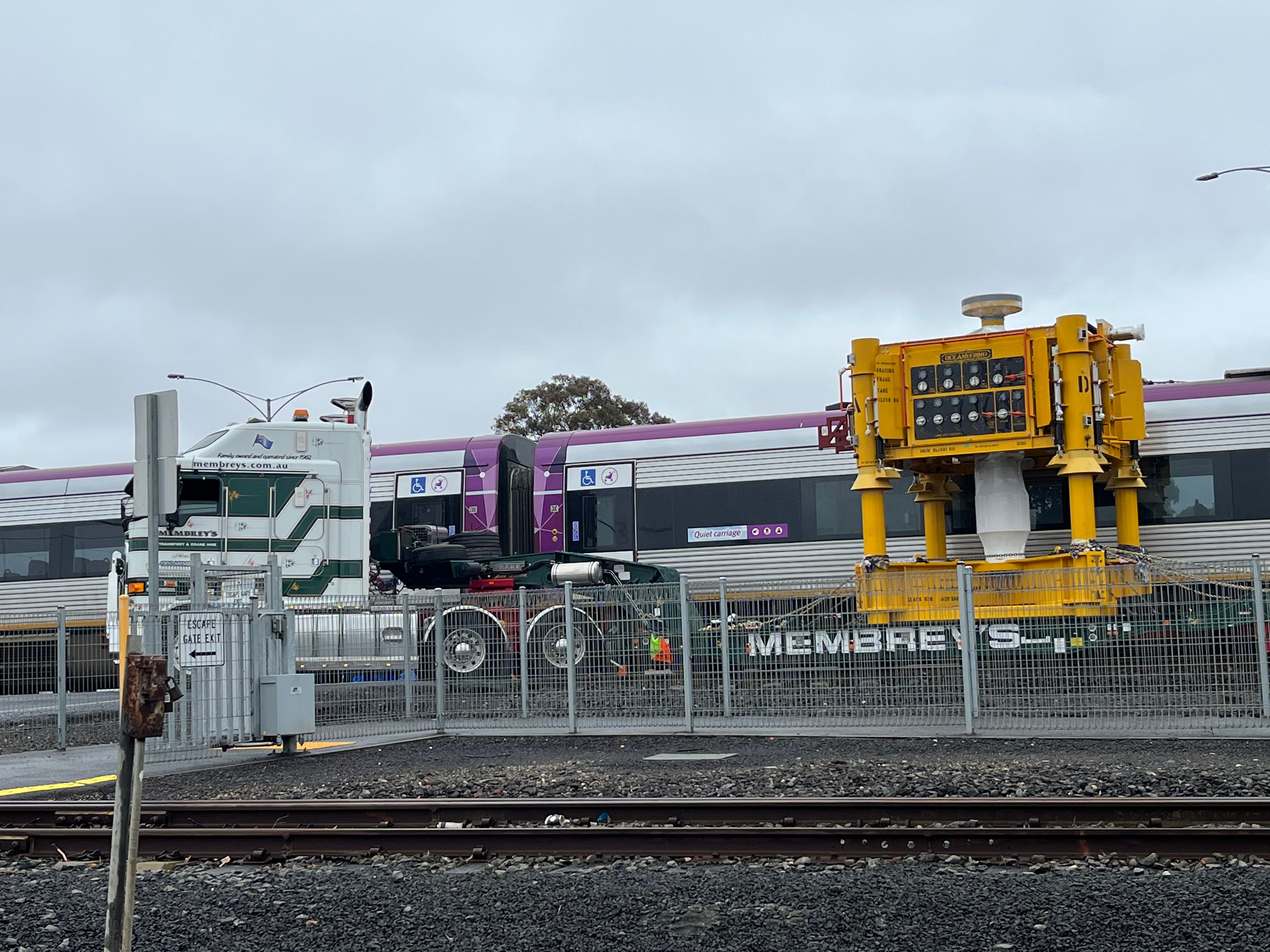 A truck and train collided at a level crossing, photographed under cloudy skies.