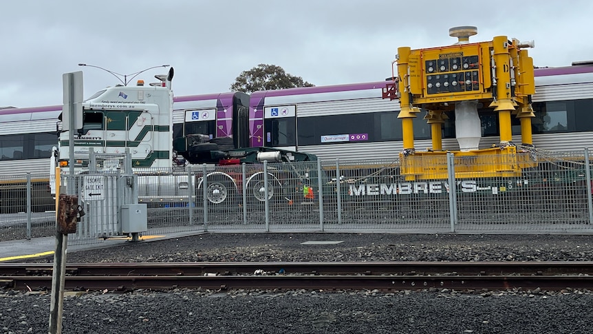A truck and train collided at a level crossing, photographed under cloudy skies.