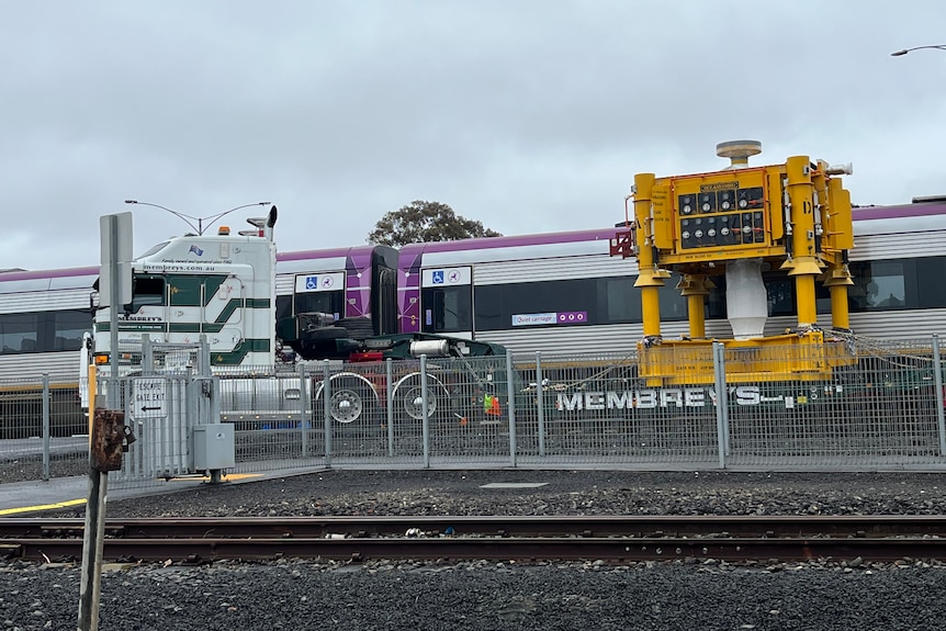 A truck and train collided at a level crossing, photographed under cloudy skies.