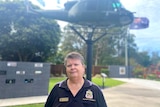 A woman stands in front of a helicopter mounted on a pole with a flag pole flying the Australian flag in the background.