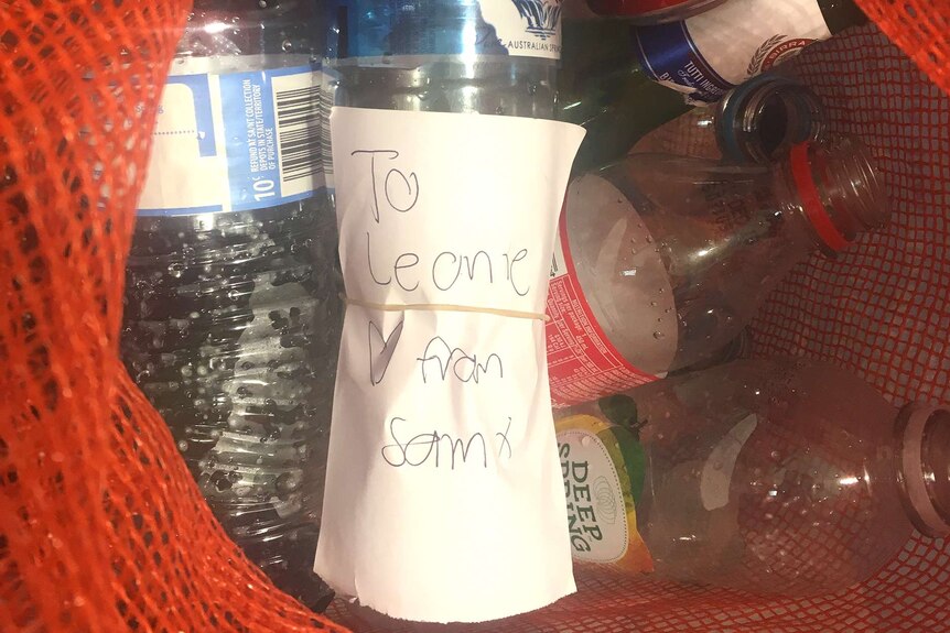 A bottle with a note saying 'To Leonie love from Sam' in a bag of bottles.