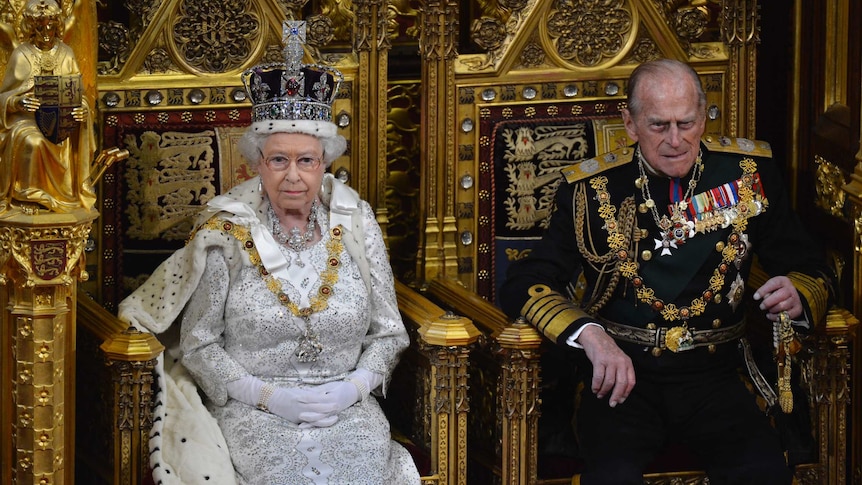Queen Elizabeth II and Prince Philip sit in elaborate gold chairs in the House of Lords.