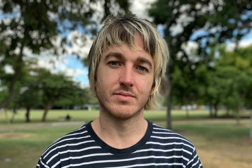 Jeremy Poxon stares into the camera with an earnest expression. He has blonde tips in his brown hair and wears a striped top.