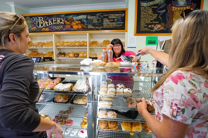 Gin Gin Bakery owner Maree Baker smiles as she serves two customers.
