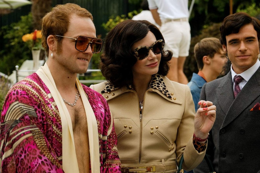 A party scene with Egerton shirtless under a pink kimono, Dallas Howard in a leopard print blazer and Madden in a suit.