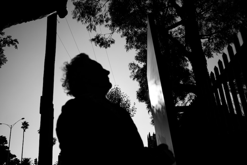 A silhouette of a woman looking at a sign. 