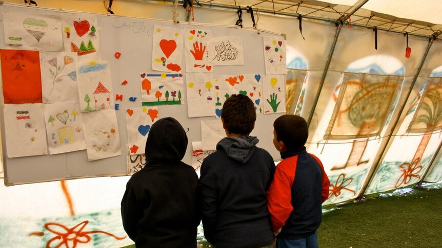 Children look at pictures at the Zaatari refugee camp