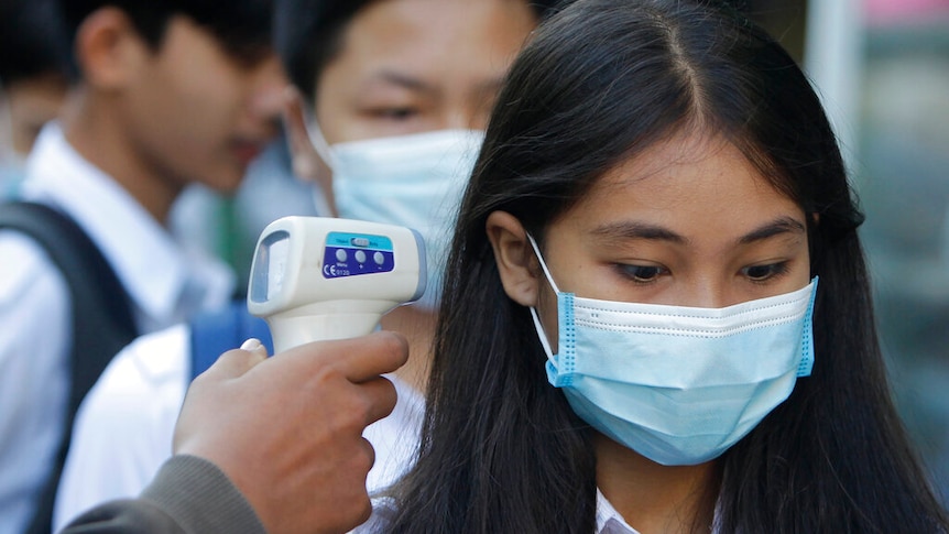 A female students has her temperature checked in Phnom Penh, Cambodia.