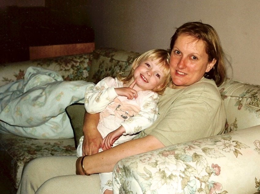 A mother hugs her small daughter on a floral couch
