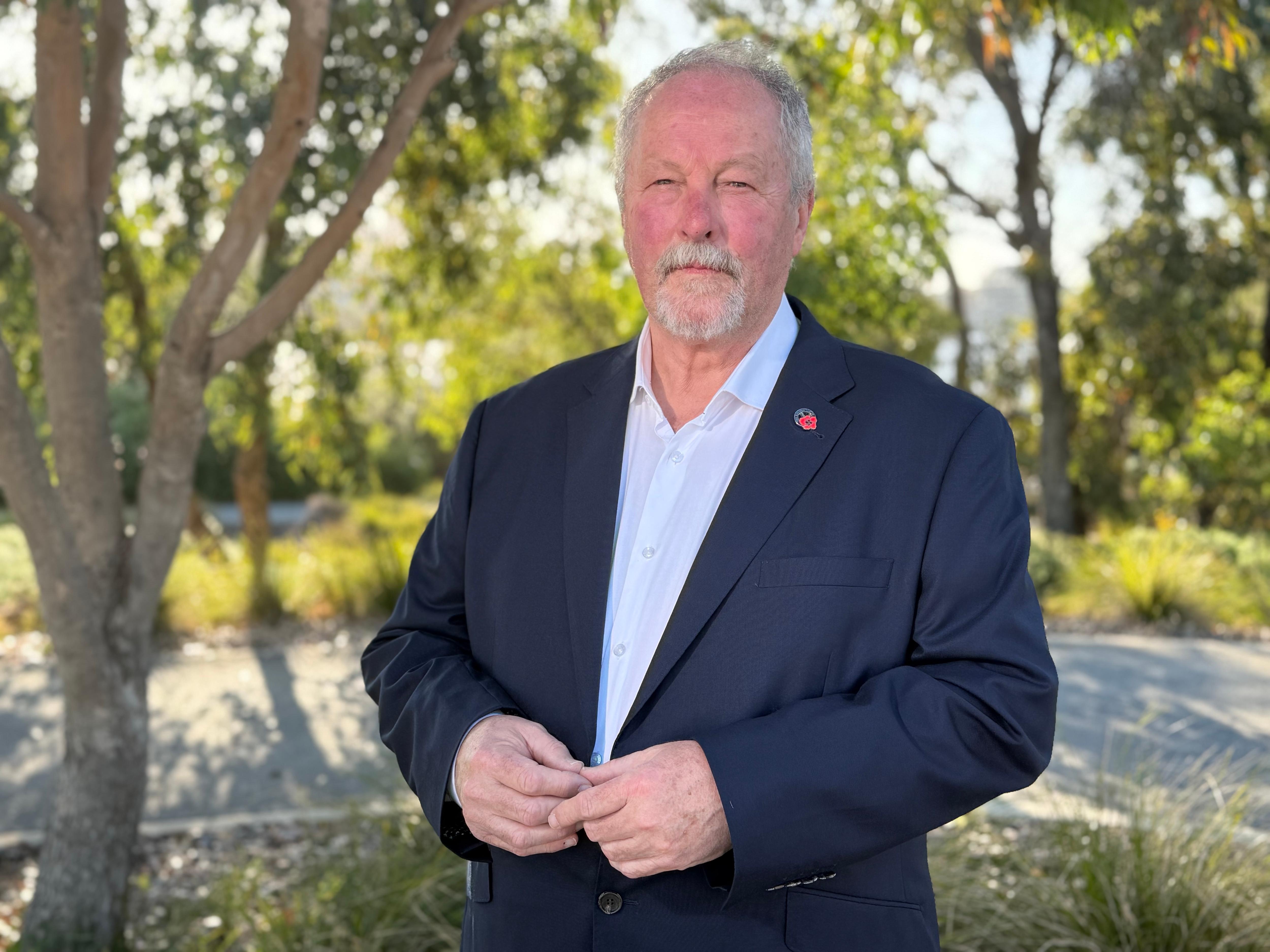 Homem vestindo terno com distintivo de papoula em pé no parque.