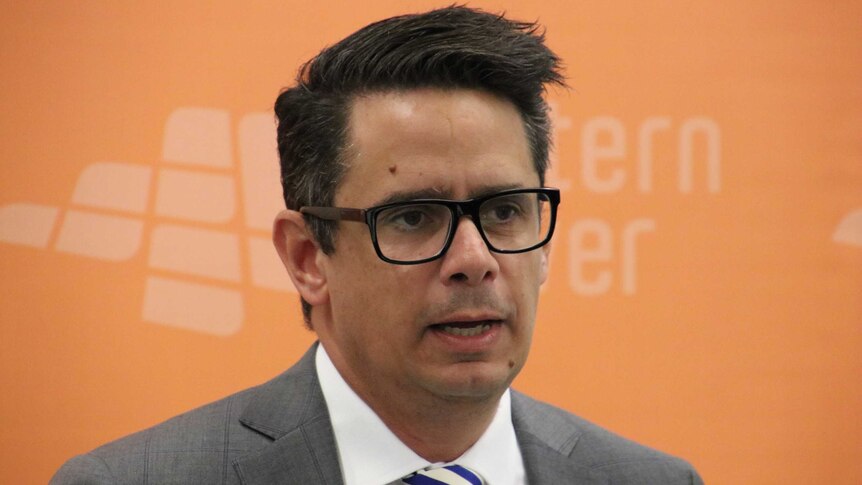 Treasurer Ben Wyatt pictured in front of an orange Western Power banner at a press conference