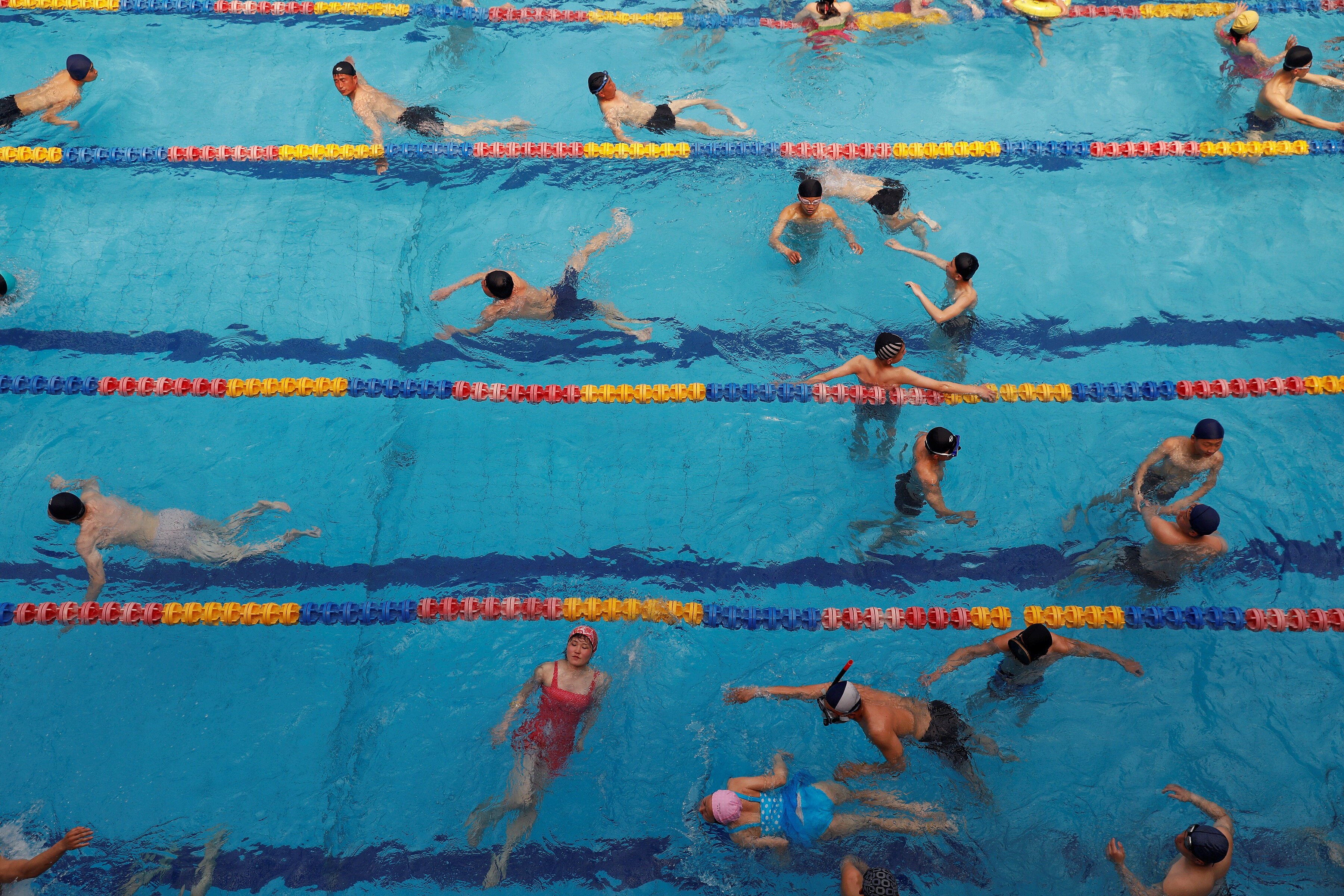 An aerial photo of a pool, as many people swim and play