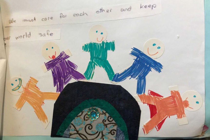 A child's drawing of five people standing on a mound says: "We must care for each other and keep our world safe"