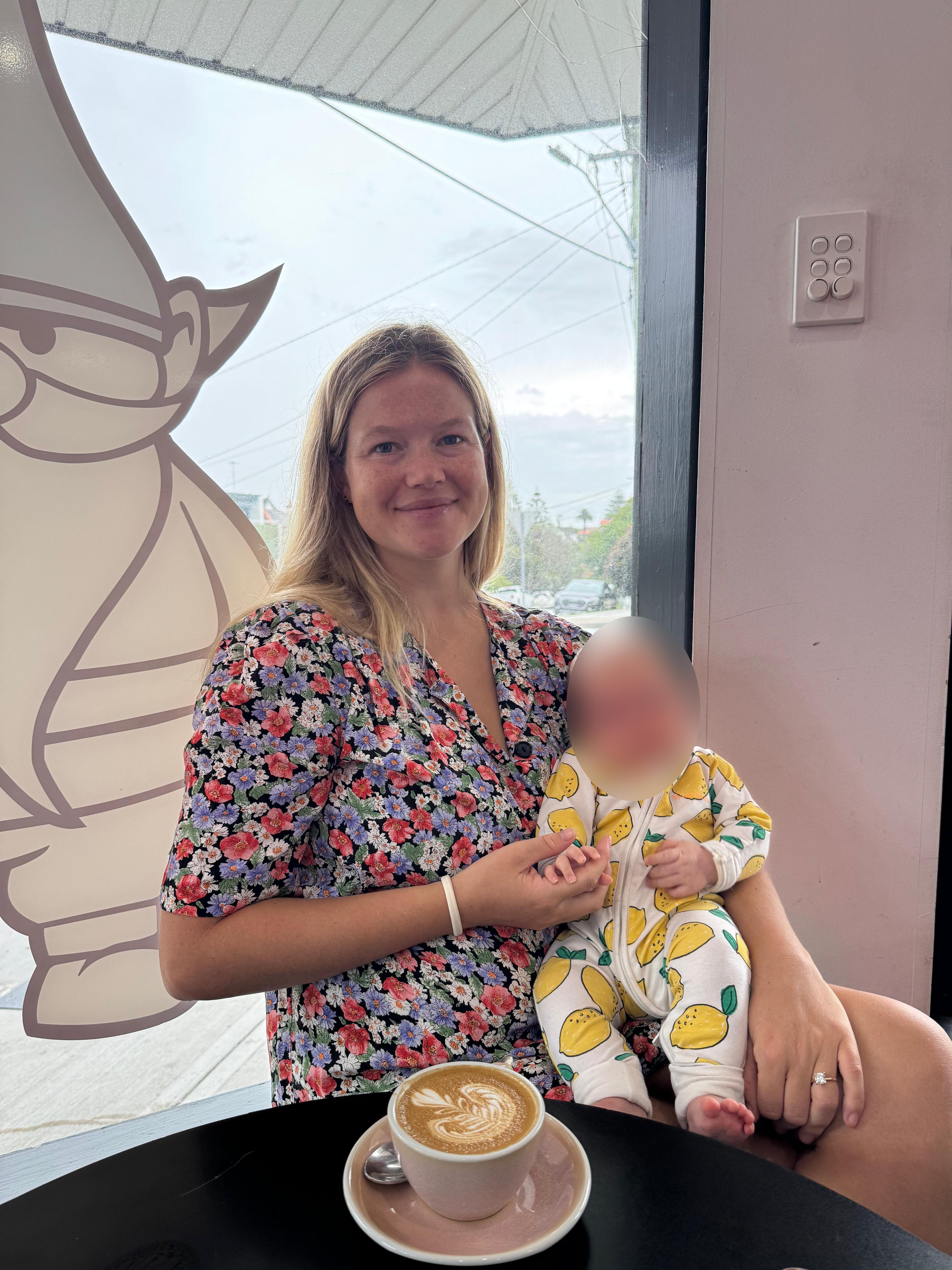Sydney mother and Coogee local, Leah Stewart, who was mauled by a shark holds a baby and looks at the camera 