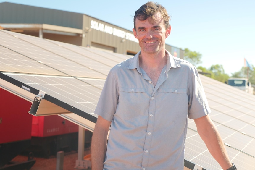 Tom Straw stands in front of a solar panel.