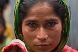 A close up portrait of an Assam woman with tears in her eyes.