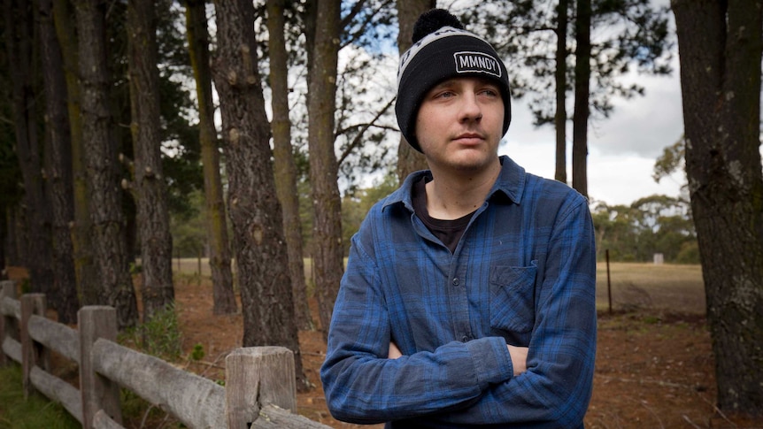 19-year-old Josh Dickinson stands against a fence on a rural property.