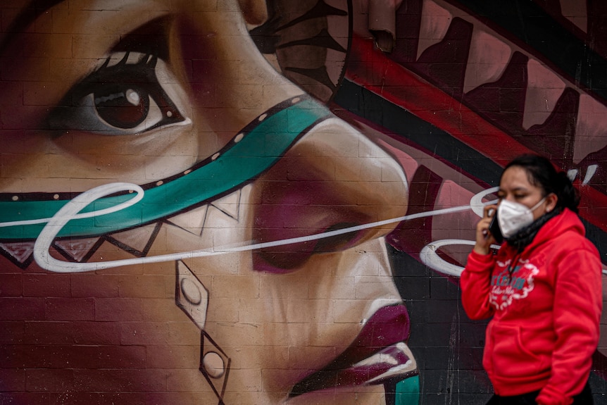 A woman walks past a mural.