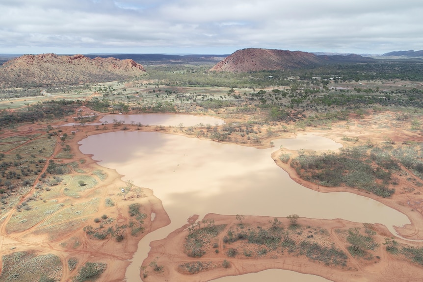 Two bodies of water surrounded by trees and hills, picture taken from up in the air by a drone.