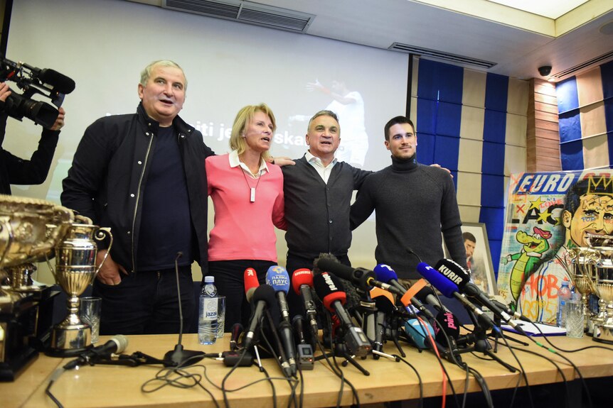 Novak Djokovic's family link arms at a press conference.