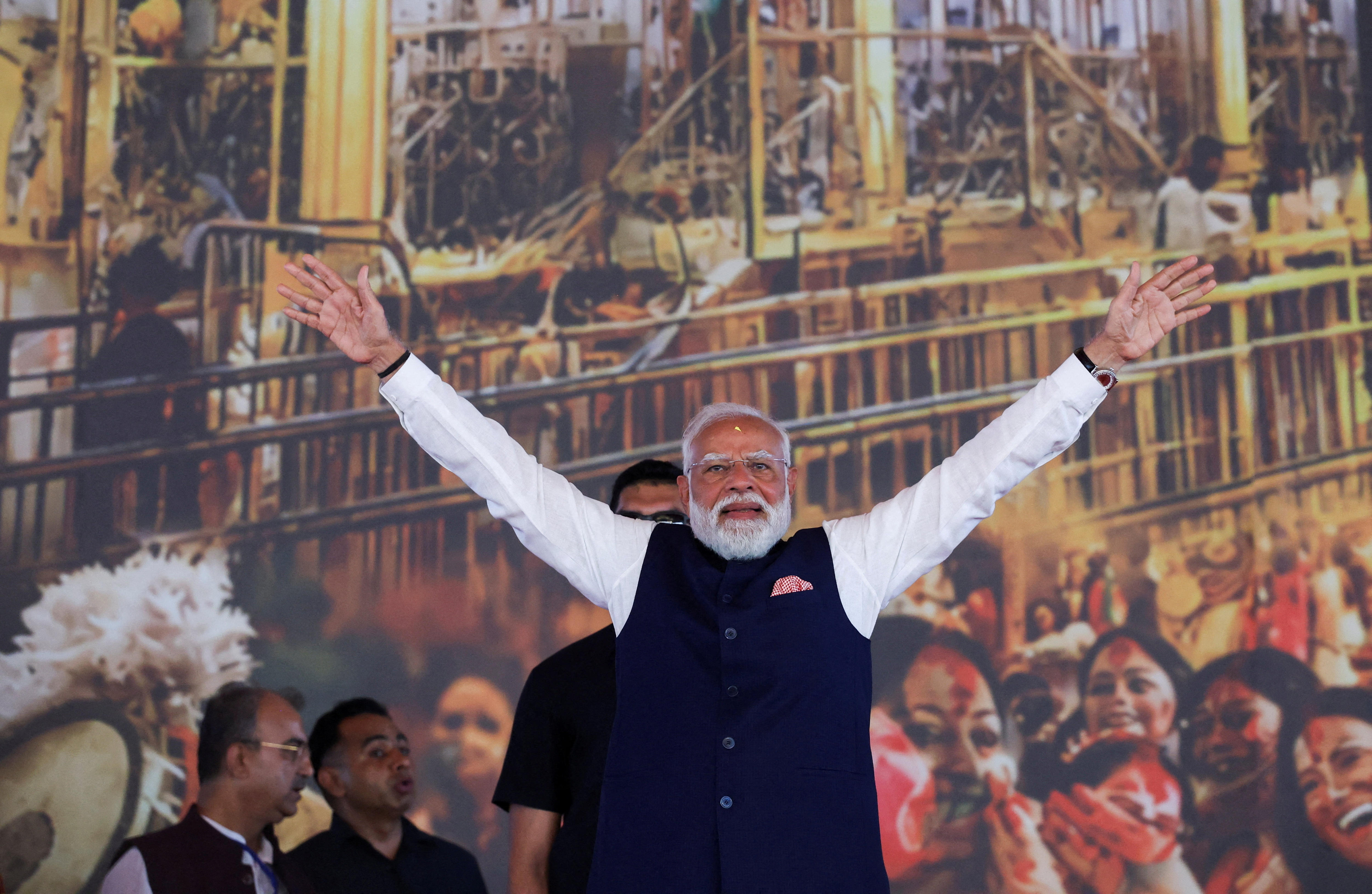 Narendra Modi stands with arms outstretched in a sign of victory.