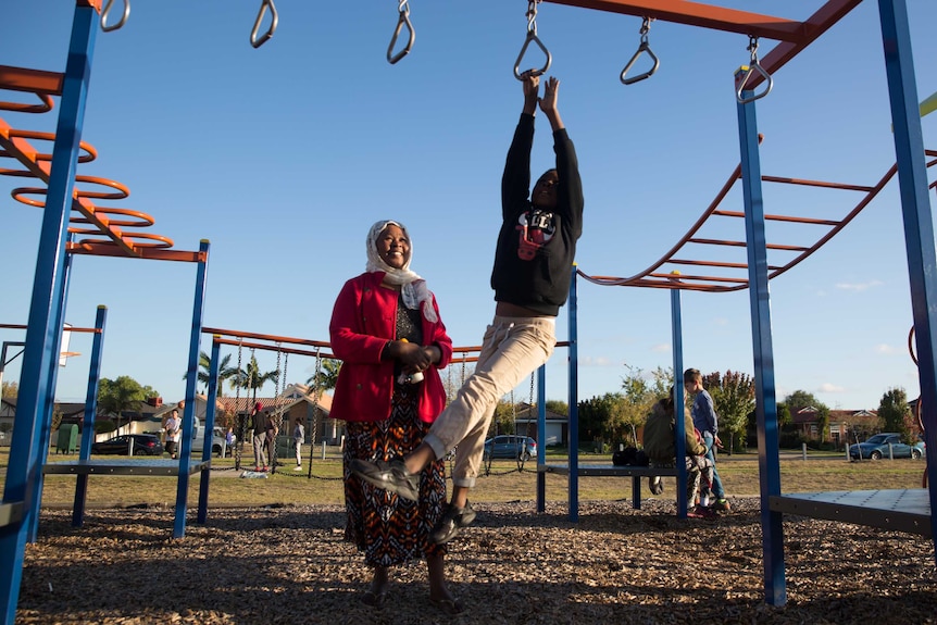 Kadiga supervises her second-youngest son Maher on the monkey bars