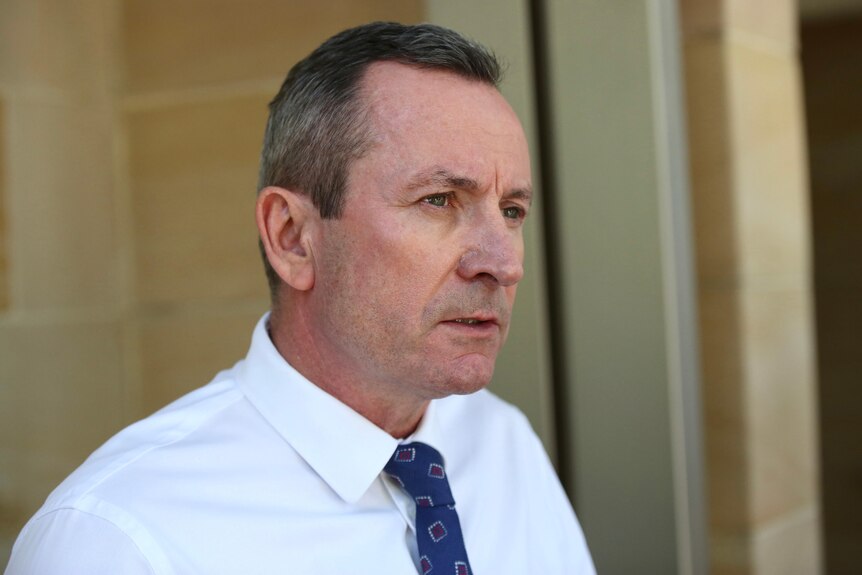 A tight head and shoulders shot of Mark McGowan outside parliament talking and wearing a white shirt.
