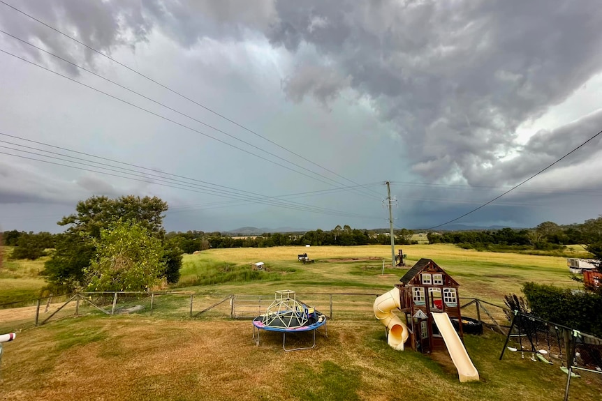 Storm approaching Kybong, in the Gympie region, green yard and playground in the foreground