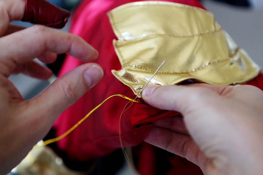 Hand sewing fabric together with needle and thread